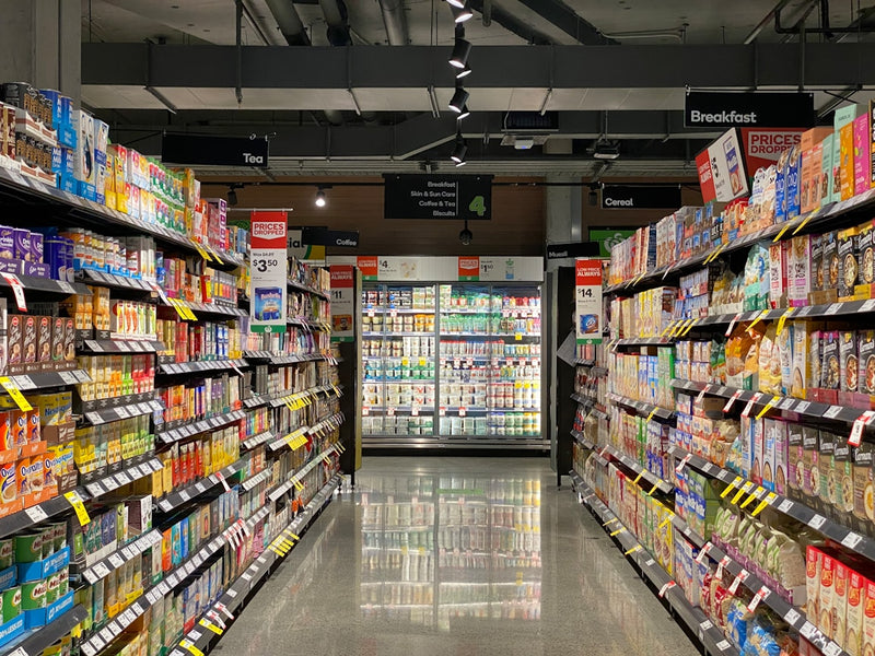 Supermarket aisle with shelves stocked with products and a central display.