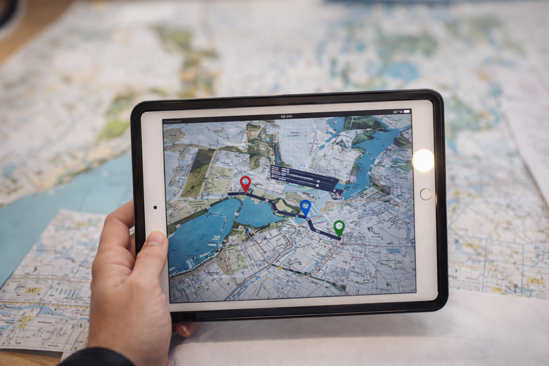 Tablet displaying a digital logistics route map with location pins over a printed city map