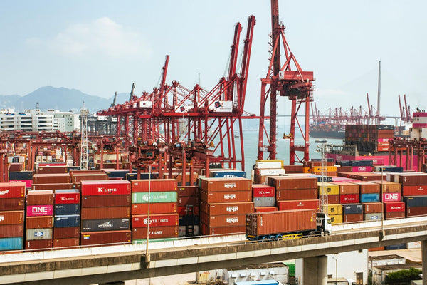 Container ship at a busy port with cranes and stacked containers.