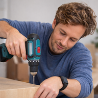 Man using a cordless drill on a wooden surface indoors
