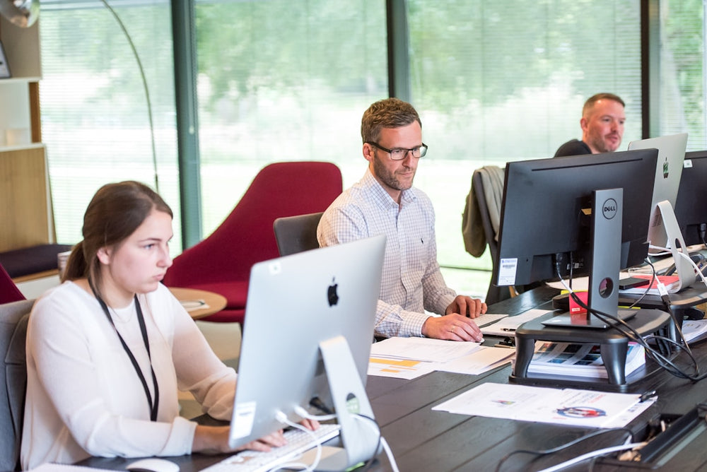 People working at desks with computers in a modern office setting