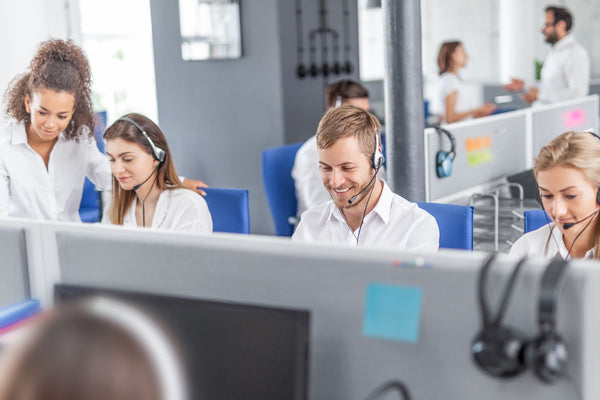 Call center agents working with headsets in a busy office environment.