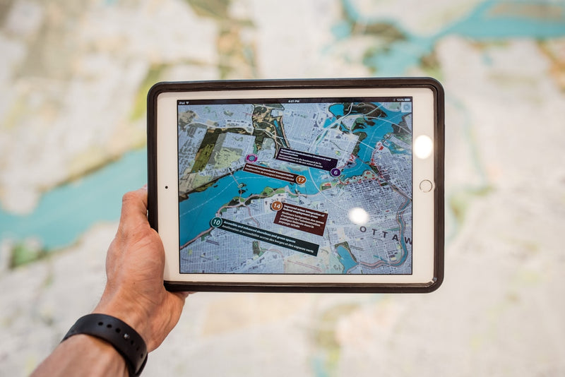 Person holding a tablet displaying a map with interactive elements.